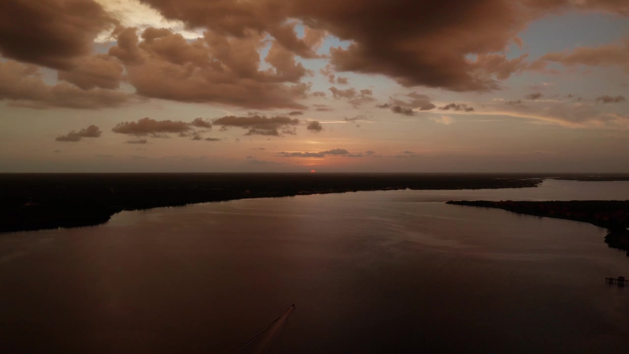 Sun dips toward the horizon over a broad river near El Jobean, with heavy clouds catching the last light. Quiet, moody landscape shot for openers or transitions.