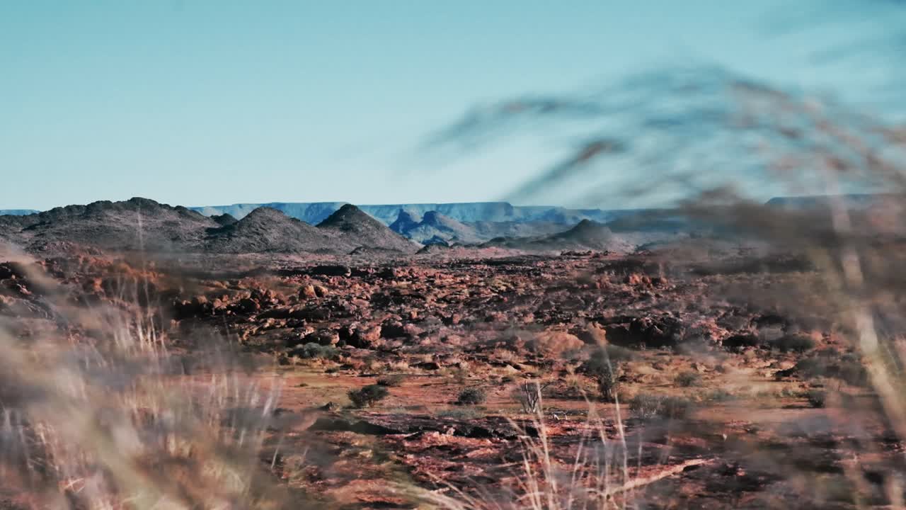 Stunning views of a dry and arid landscape of Northern Cape of South Africa with rocks and grasses in the foreground and mountains and a canyon in the distance