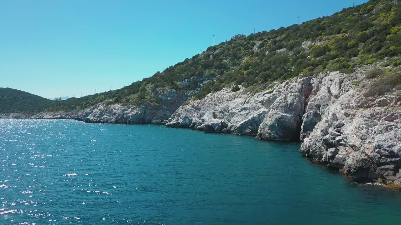 Forward drone shot next to a rocky shore in the aegean sea, Greece