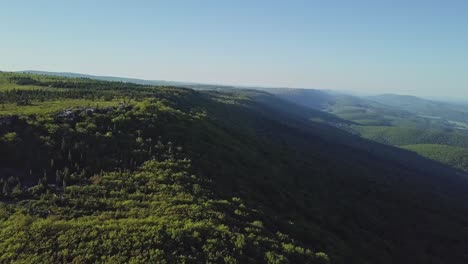 epic aerial drone shot of edge of forested mountain cinematic 4k