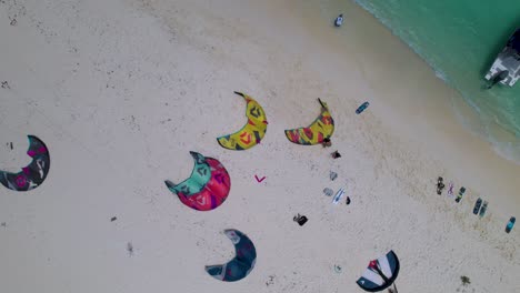 group people with kite surfing lying on sandy beach, top down aerial view los roques