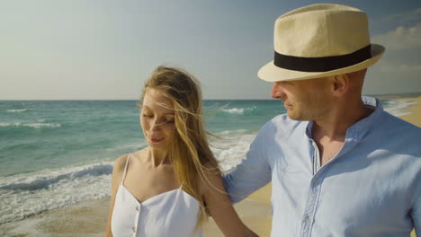 couple embracing and walking on sandy beach