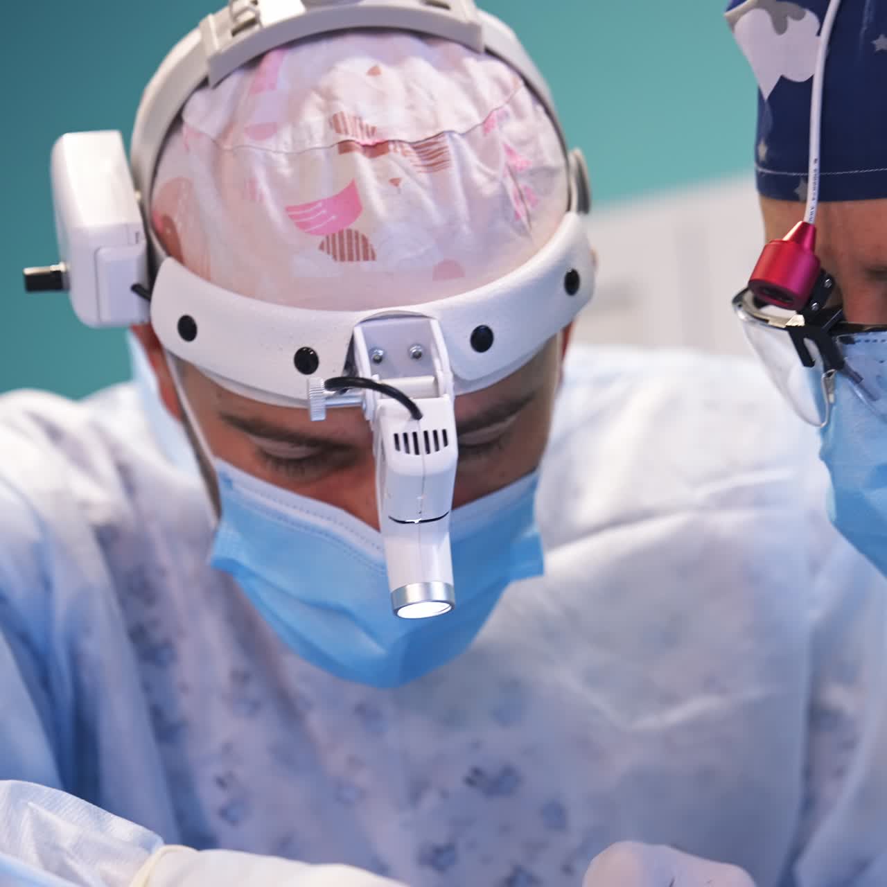 Focused surgeons collaborating at operation. Doctors use forceps and look through device glasses. Close up