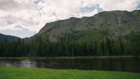 Driving-by-Yellowstone-national-park-mountain-range-and-sun-soaked-river-on-summer-road-trip-in-slow-motion