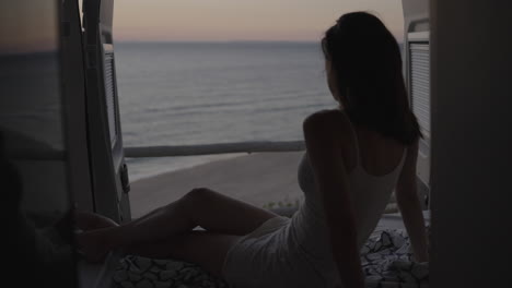 woman relaxing by ocean view from van