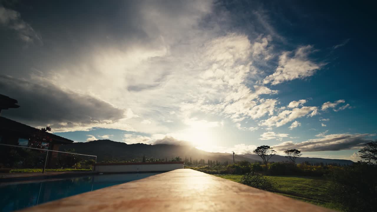 amplio time-lapse, junto a la piscina en un día de verano con nubes moviéndose en el cielo con una montaña en el fondo en oahu hawai