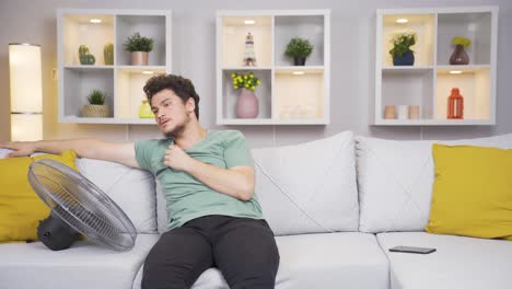el hombre que usa el ventilador está abrumado por el calor.