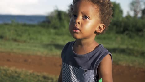 tiro de cerca en cámara lenta de un joven niño de raza mixta que vuela una cometa al sol de la tarde junto a un lago