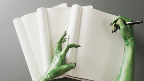 video of halloween green monster hands and notebook with copy space on grey background