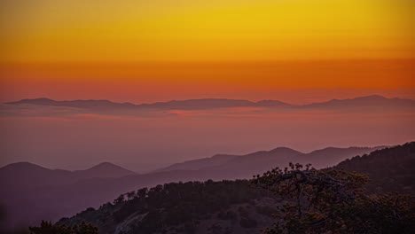 Golden-sunset-over-a-hazy-mountain-range-as-seen-from-Mount-Olympos,-Cyprus---time-lapse