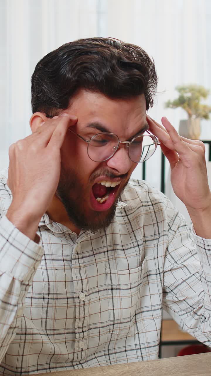 Tired ill indian businessman suffering from headache problem tension migraine stress at home office