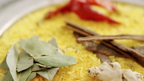 arroz con hoja de laurel, ajo, pimienta roja seca, jengibre y canela en el plato 4k