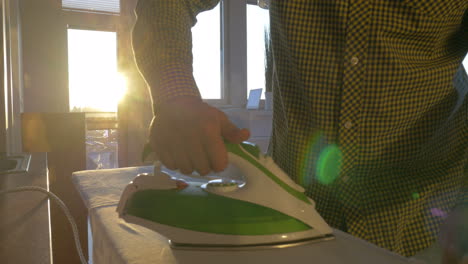 Man-ironing-shirt-in-sunny-room