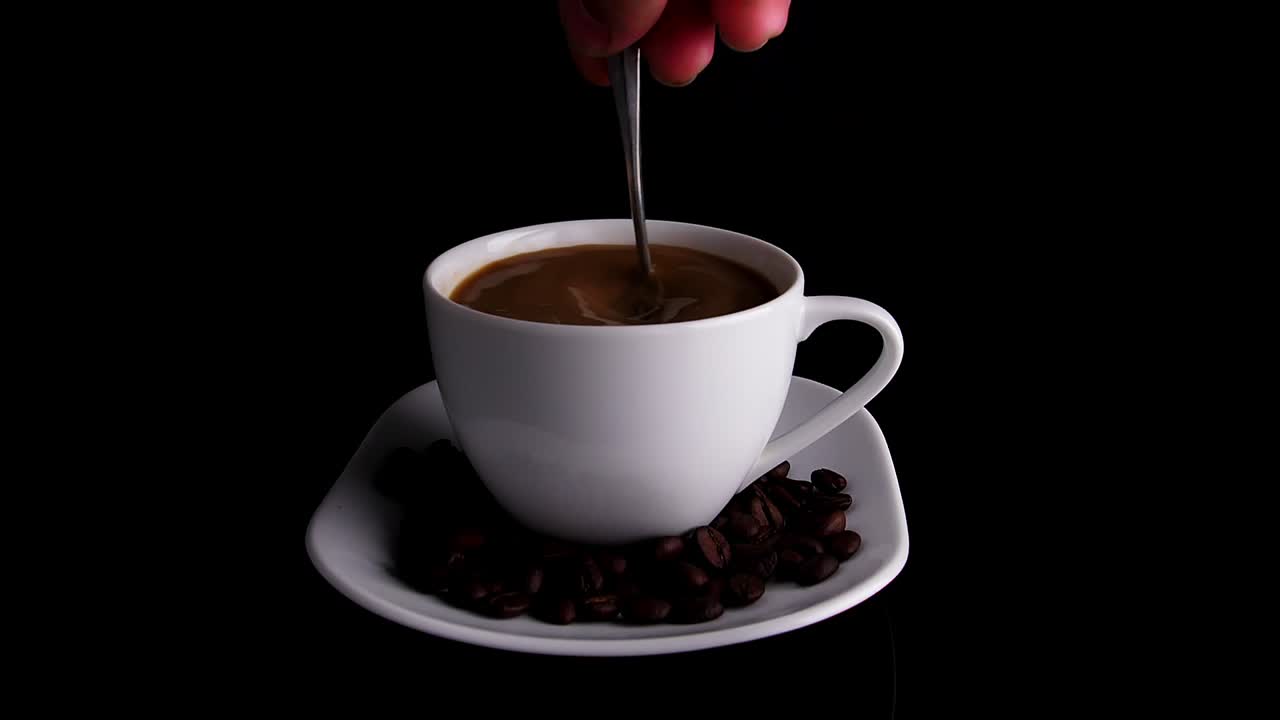 Coffee in a white cup with spoon and coffee beans
