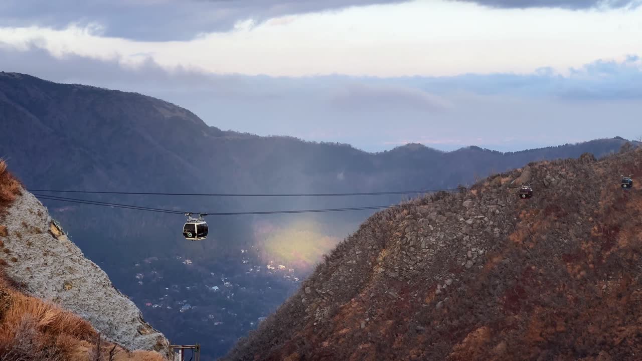 A cable car gliding over scenic Owakudani Hakone mountains with cloudy skies