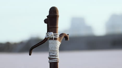 rusty old metal water pump on sand beach