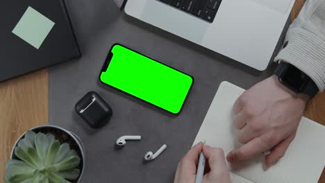 modern workspace with green screen phone and note-taking