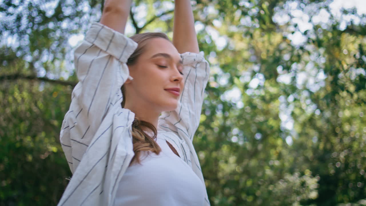 una donna che cammina ascolta musica con le cuffie wireless in una natura soleggiata da vicino.