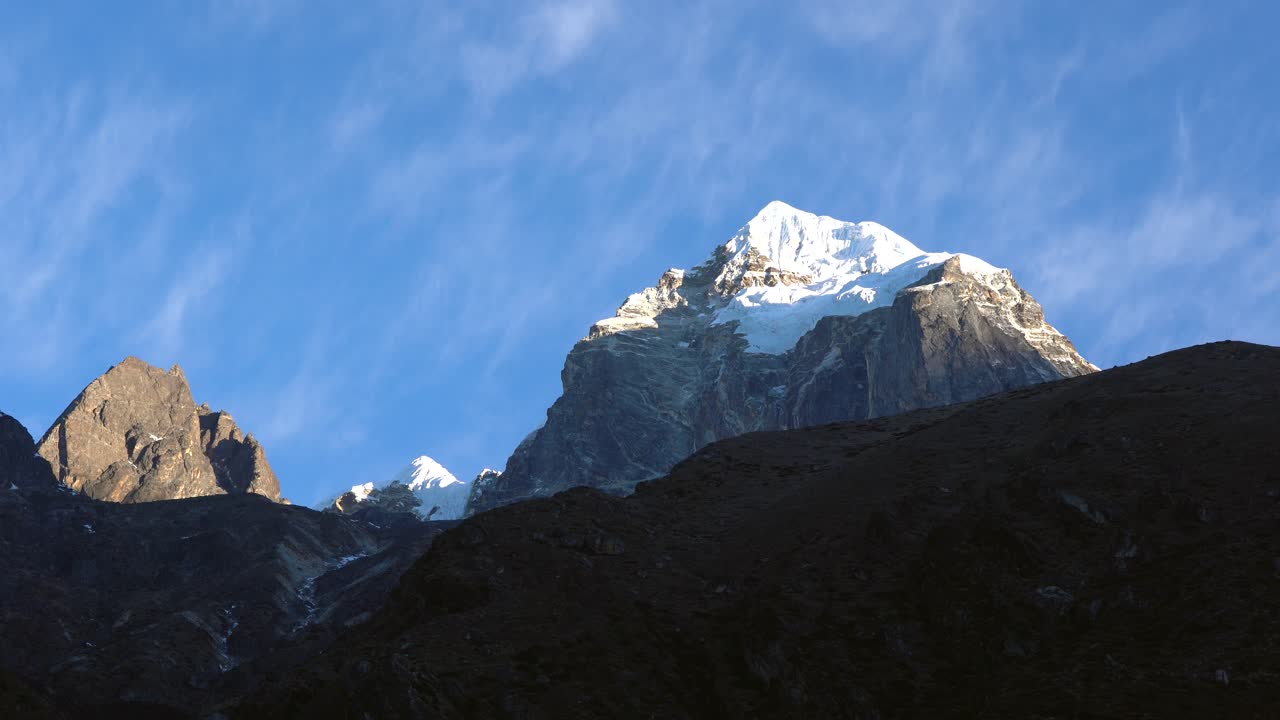 nubes moviéndose lentamente sobre el pico nevado de una montaña en el himalaya