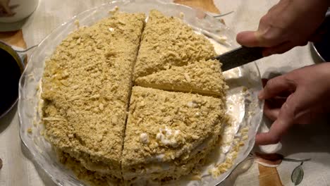 a woman cuts a honey cake into pieces with a big knife on a holiday. close up. the view from the top. 4k.