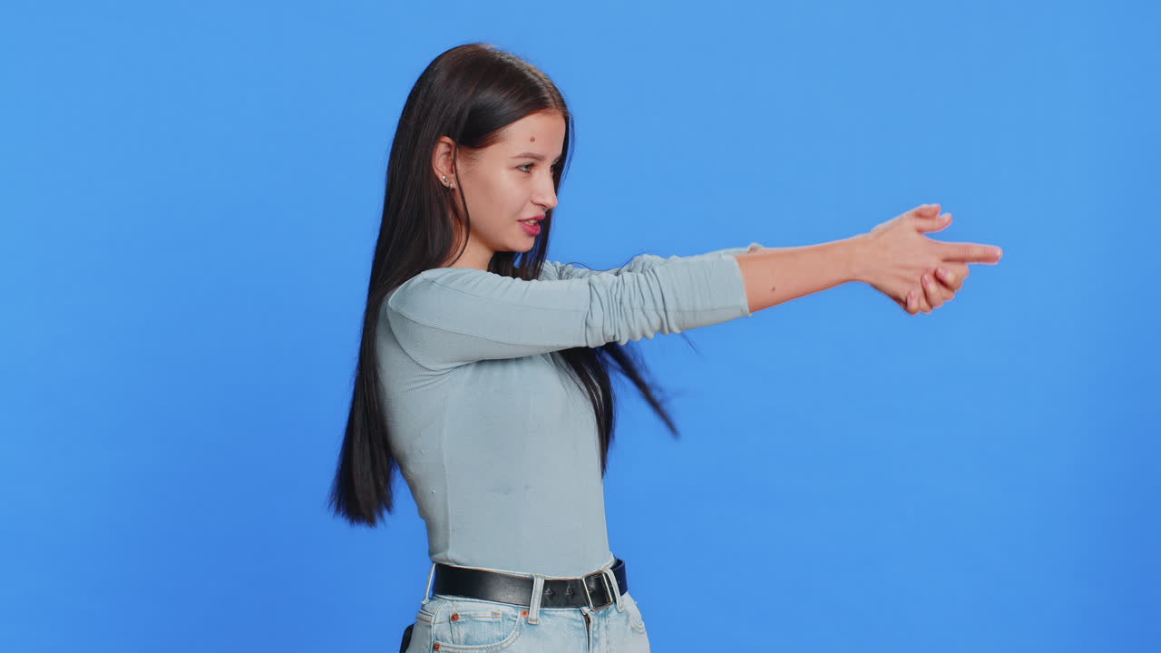 Woman pointing around with finger gun gesture making choice shooting killing with hand pistol