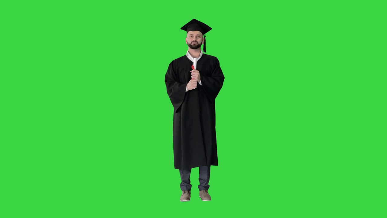 Giovane uomo felice con cappello da laureato che tiene in mano il diploma e parla su uno schermo verde, Chroma Key