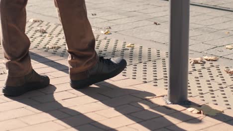 lone blind man detecting tactile tiles, walking to pedestrian crossing safe road