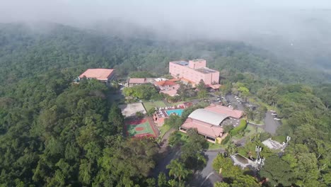 aerial view of a resort in embu das artes, são paulo, surrounded by lush green forest and misty hills