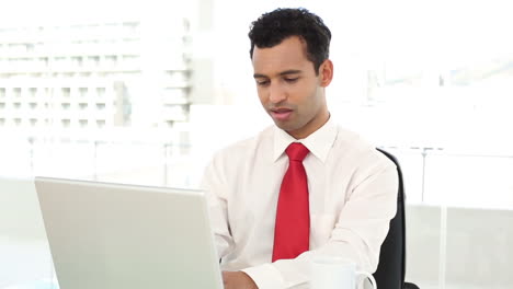 Smiling-handsome-businessman-typing-on-laptop