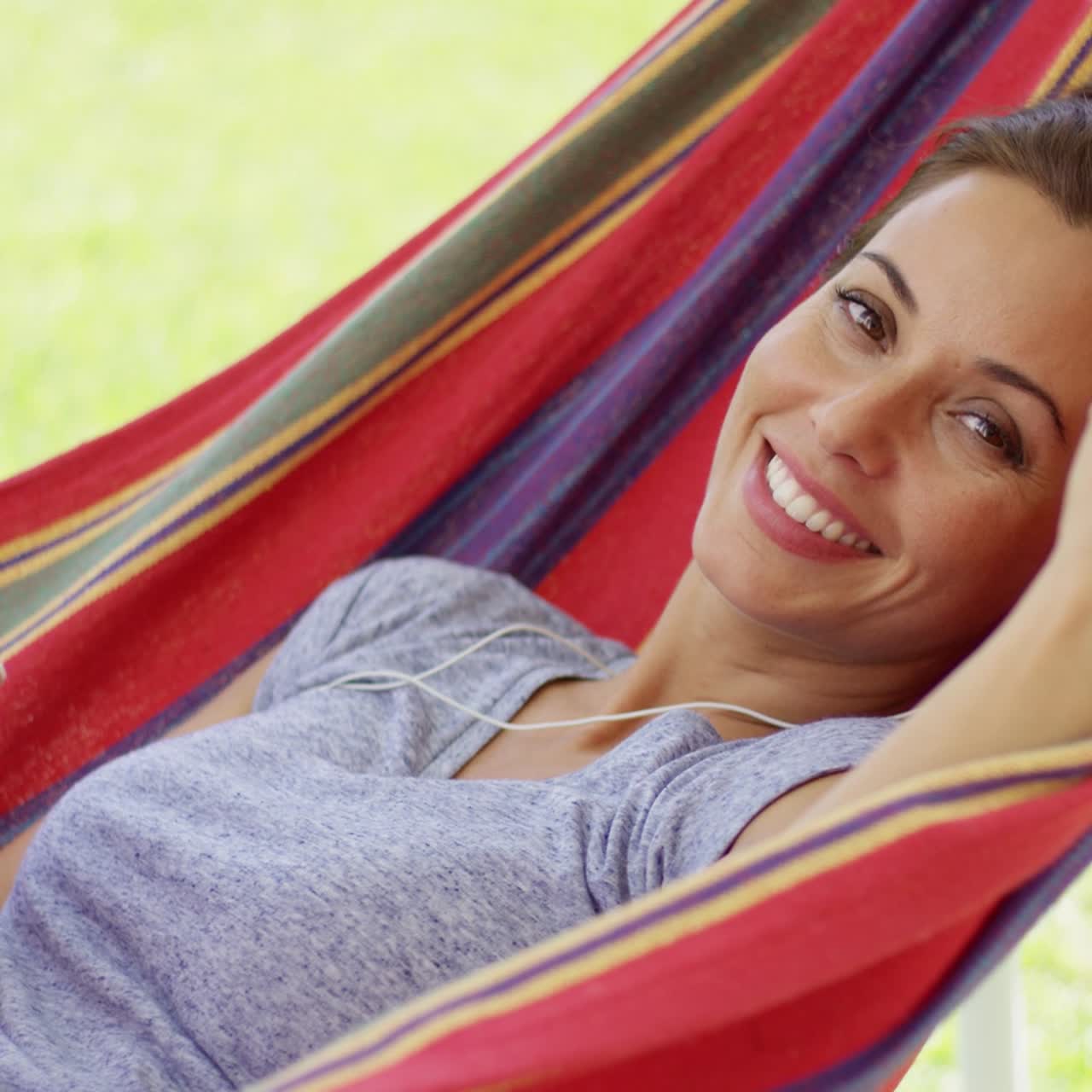 mujer joven feliz escuchando música en una hamaca