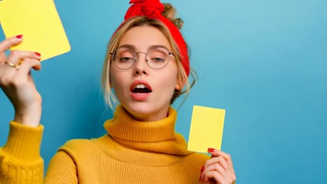 una mujer con un suéter amarillo sosteniendo dos tarjetas amarillas en sus manos