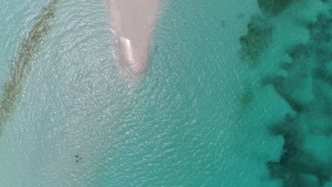 Aerial-top-view-tropical-sandbank-with-3-people-stand-on-shades-of-bluewater,-water-texture