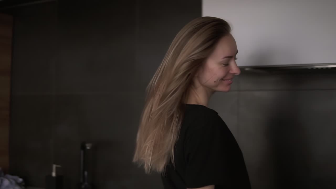 A cheerful woman with a ladle in a modern kitchen pretends to sing