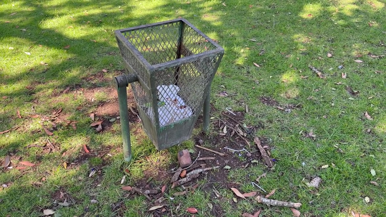 Cestino dei rifiuti in rete metallica usurata in un parco