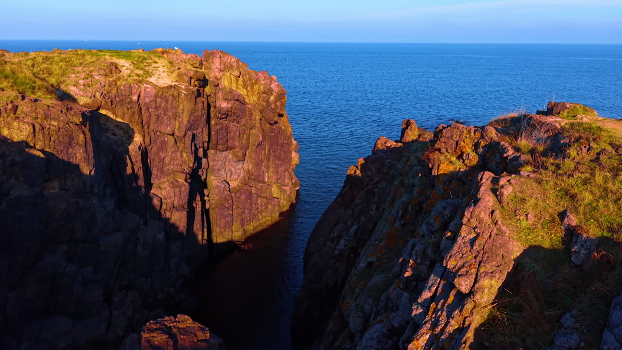 Optagelser blandt de solbeskinnede klipper ved kysten af havet eller oceanet. Afslørende udsigt over det store, blå, endeløse vandlandskab.
