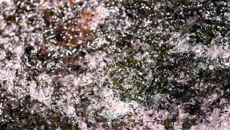 tight shot of water flowing over a rock in slow motion