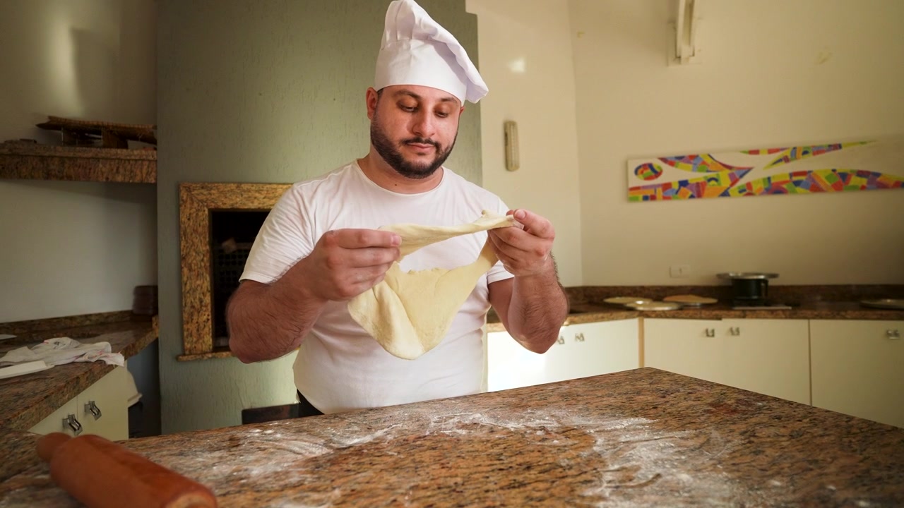 Um chef profissional segura massa que não deu certo nas mãos, expressando frustração e decepção em um ambiente de cozinha.