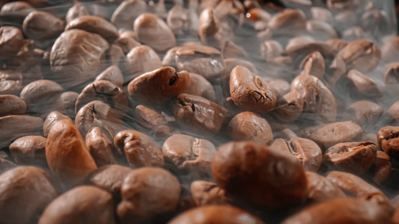 Close up of seeds of coffee. Fragrant coffee beans are roasted smoke comes from coffee beans.