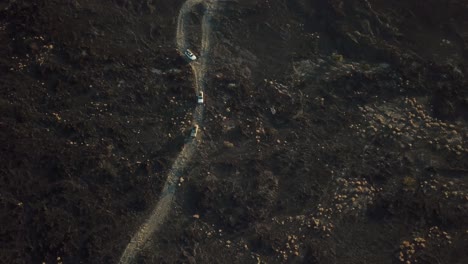 Convoy-of-3-jeeps-driving-over-lava-field,-Erta-Ale-volcano,-Ethiopia---aerial