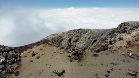 Aerial-orbits-person-standing-on-rim-of-volcano-crater-in-Guatemala