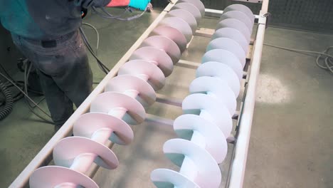 aplicación de recubrimiento de polvo blanco anticorrosión en dos rotores industriales de metal con pistola perdida en una planta