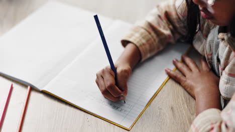 child learning to write alphabet in notebook