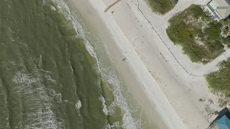 Aerial-zoom-out-of-couple-walking-along-the-beach-at-Cape-San-Blas,-Florida