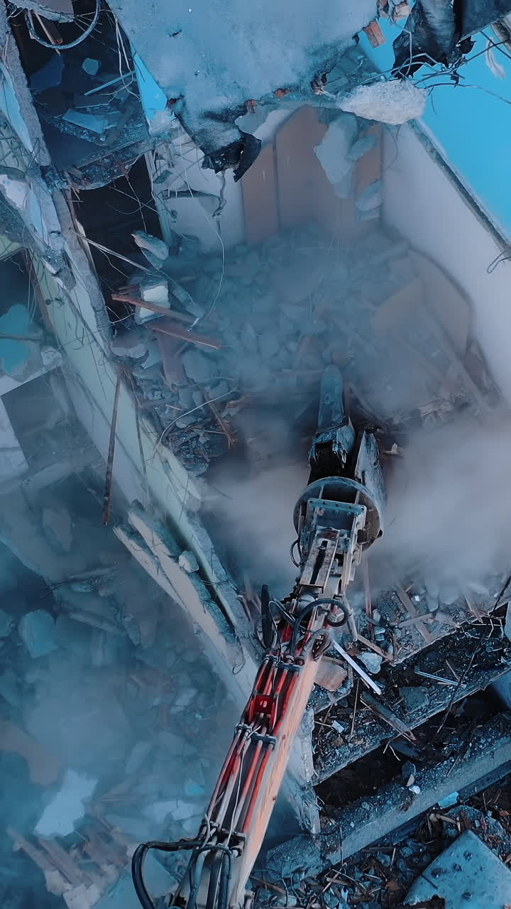 Process of dismantling a structure after an earthquake. Destruction of walls and concrete blocks that were broken by the earthquake. Excavator dismantling high buildings. Vertical video
