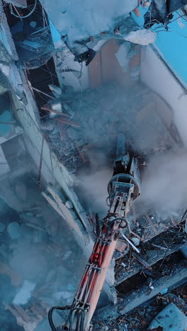 process of dismantling a structure after an earthquake. destruction of walls and concrete blocks that were broken by the earthquake. excavator dismantling high buildings. vertical video
