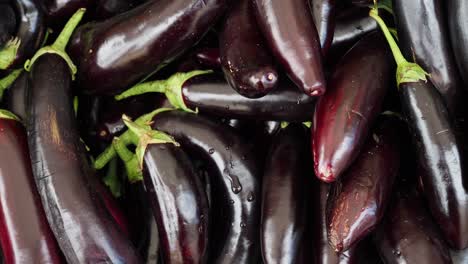 close-up view of a pile of fresh dark purple eggplants