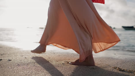 Friedlicher-Strandspaziergang-Mit-Diesem-Nahaufnahmevideo,-Das-Die-Füße-Einer-Frau-Einfängt,-Während-Sie-In-Einem-Fließenden-Kleid-Am-Sandstrand-Entlang-Spaziert