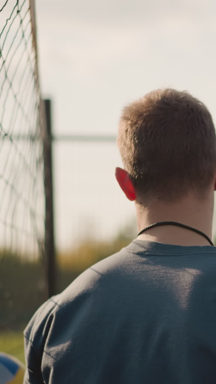 Uomo visto da dietro che gioca a pallavolo con una donna che schiaccia la palla sulla rete in primo piano, donna leggermente sfocata sullo sfondo, partita di pallavolo all'aperto incentrata sull'azione sotto un cielo luminoso