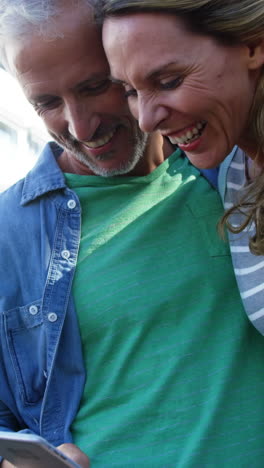 una pareja madura está sonriendo y mirando un teléfono inteligente