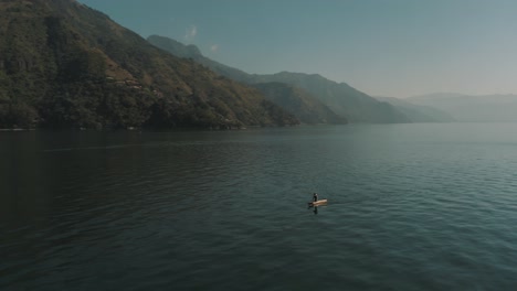 drone aerial rotating around a man on a boat during beautiful sunrise in lake atitlan, guatemala